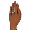 A digital rendering shows a solid 14k white gold ribbed ring worn on a medium/tan-toned hand with rose-colored manicured nails. The ring features a lab-created alexandrite in a circular bezel setting, displaying deep blue tones against the bright white metal. The band's horizontal ridged texture wraps completely around the finger, creating a contemporary linear pattern. The ring is positioned on the third finger, with the hand elegantly posed against a clean white background, fingers slightly spread to showcase the modern design.