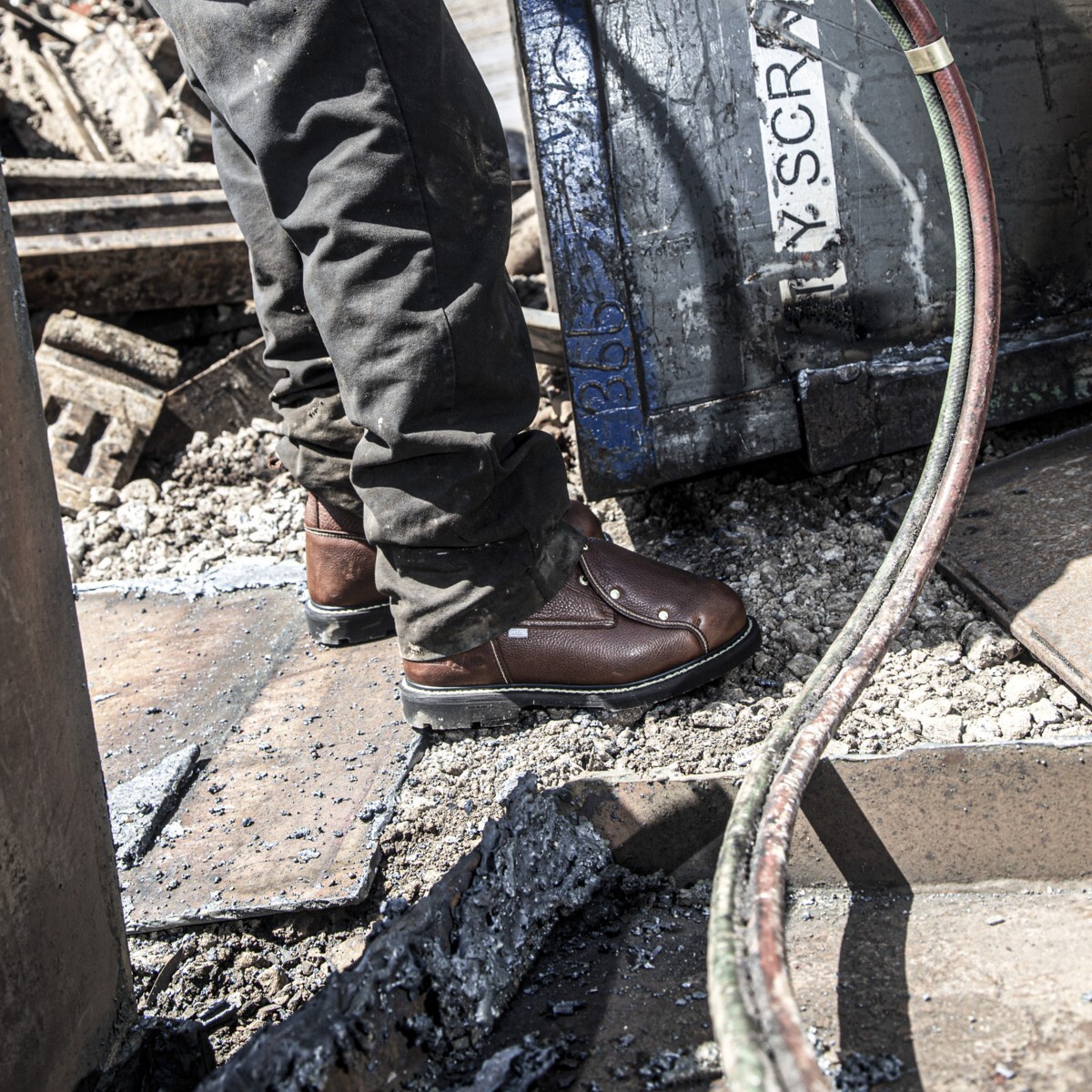 groundbreaker-ia5015-ia5017-img-1398-square.jpg Junk yard worker wearing electrical hazard boots standing next to an electrical cable