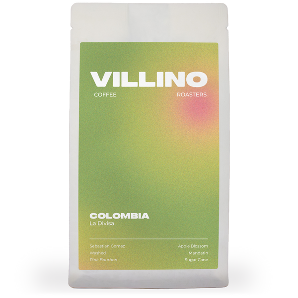 A white bag of single origin coffee with a light green and peach label. The white letters at the top of the label reads "Villino Coffee Roasters",  and the small white text at the bottom reads "Colombia La Divisa".