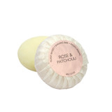 A round bar of Heaven Scent Heritage natural origin shaving soap, pleat wrapped in white paper. The top features a pale pink circular label for the Rose & Patchouli scent.  Made in the UK using sustainable plant-based ingredients.