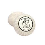 Heaven Scent Bergamot, Rose & Patchouli natural origin shaving soap. The round, plant-based soap is shown wrapped in traditional pleat paper, sealed with a circular label featuring a black and white Sarah Pettitt illustration of a lady.