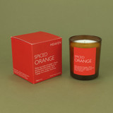 Heaven Scent Spiced Orange natural soy and plant wax scented candle in a brown glass jar displayed beside its matching zingy orange presentation box against a green botanical background