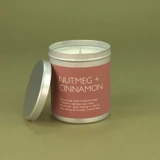 Heaven Scent Nutmeg & Cinnamon festive vegan natural soy and plant wax scented candle in a travel tin displayed beside its lid against a green botanical background
