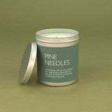 Heaven Scent Pine Needles festive vegan natural soy and plant wax scented candle in a travel tin displayed beside its lid against a green botanical background