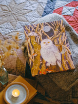 Wholesale 12-day Christmas advent calendar with a snowy owl illustration by Sarah Pettitt, displayed alongside three scented soy tealights.