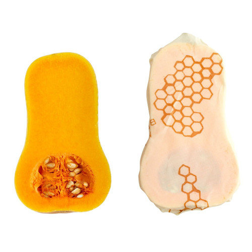 A single large Bee's Wrap in Honeycomb print wrapping a cut butternut squash with the other half laying alongside of it.