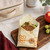 A Bee's Wrap Sandwich Wrap in Honeycomb Print with a sandwich, apple, and a lunchbox.