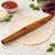 An Ironwood French rolling pin on a kitchen counter with pizza dough.