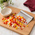 The Fox Run Stainless Steel Chopper Scraper on a wooden cutting board, scooping up diced peppers and onions.