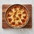 A Mrs Andersons Baking Nonstick Springform Pan filled with a baked pizza on a cutting board on a kitchen counter