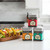 Three tins from the Spicewalla Taco Collection are stacked on a kitchen counter in front of a serving tray of tacos.