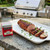 A tin of Spicewalla Carolina BBQ Rub on a stone table with a grilled pork loin on a white plate.
