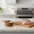 The RSVP Olive Wood Salt Box is filled with two kinds of salt (not included) on a kitchen island next to chicken breasts on a cutting board, ready to be seasoned.