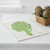 The Wet-It! Artichoke Swedish Cloth on a kitchen counter next to a basket of artichokes