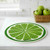 A Wet-It! Lime Round Swedish Cloth on a kitchen counter with a basket of green apples