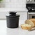 A classic black matte Butter Bell Crock on a kitchen island with a buttered slice of a baguette