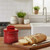 The Cafe Retro Butter Bell Crock in Maraschino Red on a kitchen island with a baguette on a cutting board