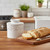 The white linen Antique Butter Bell Crock on a kitchen island with a baguette on a cutting board