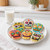 Decorated cookies made with the Tovolo Sugar Skull Cookie Cutters Set on a plate next to a glass of milk.