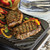 Nordic Ware Two Burner Reversible Griddle grilling steaks on a stovetop