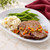 A meatloaf dinner with mashed potatoes and green beans on a white plate.