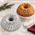 A cake baked in the Nordic Ware Stained Glass Bundt Pan is being decorated on a cake stand.