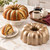 The Nordic Ware Original Bundt Pan on a kitchen counter with a pistachio-glazed bundt cake and coffee.