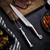 Hammer Stahl Carving Knife & Fork Set leaning on a cutting board with a steak