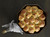 Overhead view of a well lit FINEX 10-Inch Cast Iron Skillet with fresh baked dinner rolls on a table.