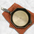 Overhead view of a FINEX 10-Inch Cast Iron Skillet on a burnt orange kitchen towel on a marble counter.