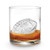 An ice football made with Tovolo Football Ice Molds in a glass with brown liquid and a white background