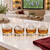 Each of the four sports ball ice shapes in a rocks glass with bourbon on a kitchen island with a football game on a TV in the background.