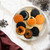 Cookies made with the Nordic Ware Halloween cookie stamps on a plate on a Halloween-decorated marble counter.