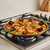 A Belseher paella pan on a stovetop filled with seafood paella