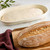 Proofing dough in an Eddingtons 16-inch Oval Banneton Proofing Basket alongside a baked loaf of bread on a cutting board