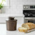 The bronze matte Butter Bell crock on a kitchen island with a buttered slice of a baguette