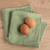 The Now Designs Ripple Sage Green Cotton Dish Cloths on a counter with eggs