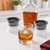 A tennis ball ice in a rocks glass with bourbon and the ice molds on a kitchen island.