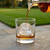 A tennis ball ice in a rocks glass with bourbon being poured on top.