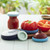 The five sizes of the Food Huggers in Ice Blue with fruit and a jar on a cutting board