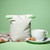 A closed Food Huggers Fabric & Silicone Reusable Coffee Bag with a cup of coffee