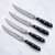 The knives of the Messermeister Avanta Black Steak Knives set on a marble counter
