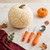 A white pumpkin with a pretty etched vine-and-leaves design, alongside the Messermeister pumpkin carving tools set.