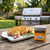 A Spicewalla Carolina Mustard BBQ Rub tin sits on a wooden table beside a platter of seasoned pork chops.