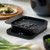 The black Rosti Mensura Kitchen scale weighing beans on a kitchen counter