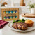 The  Spicewalla Signature Gift Set on a kitchen island with a chicken thigh and corn muffin dinner.