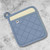 An overhead view of the Now Designs Superior Slate Blue Pot Holder on a marble counter