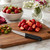 The Messermeister Pro Series Spear Point 4 inch paring knife on a wooden cutting board with hulled strawberries.