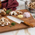 The Messermeister Oliva Elite 7 Inch Santoku Knife with mushrooms, shallots, garlic, and thyme on a cutting board.