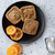 Cookies made with the Nordic Ware Fall Forest Springerle Cookie Stamps on a black plate next to orange slices